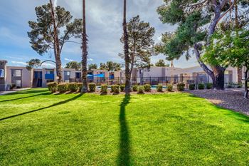 A well-maintained lawn with trees and a row of houses in the background.